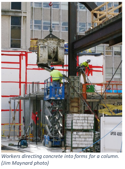 Workers directing concrete into forms for a column.