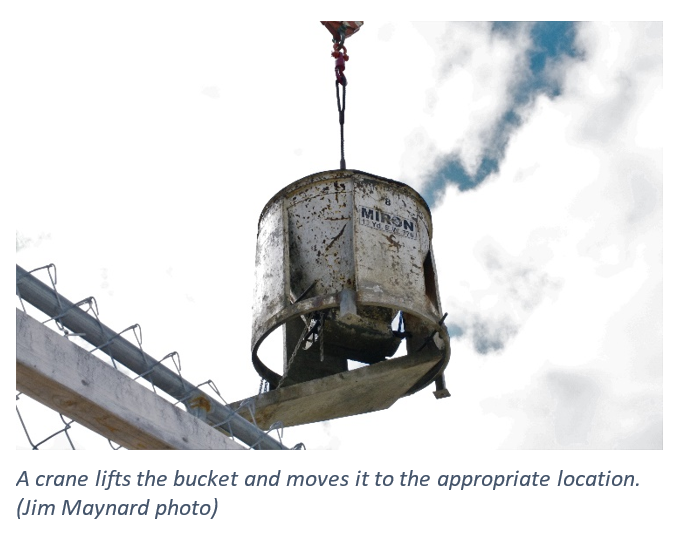 A crane lifts the bucket and moves it to the appropriate location.