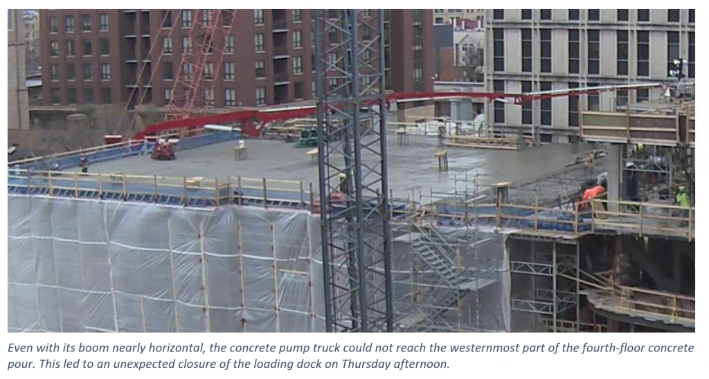 The boom arm of a concrete truck reaches toward a cement pour location.