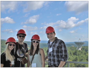 students outside with red hardhats on and green trees in the background